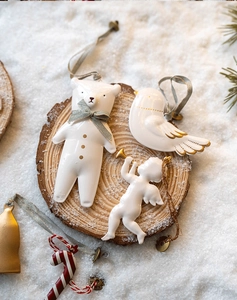 Close-up of white ceramic Christmas ornaments: polar bear, bird, and angel on snowy wood