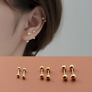 Trois paires de boucles d'oreilles barbell en argent S925 doré de tailles variées sur un modèle