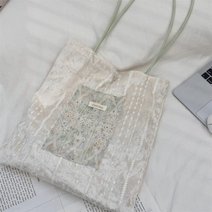 Détail du sac cabas en dentelle vintage avec texture florale et anses vert clair
