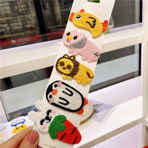 Detailed view of five knitted cartoon animal hair clips on white card packaging