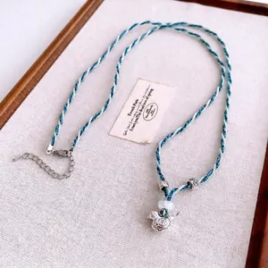 Collier artisanal en corde bleue et blanche avec pendentif oiseau et détails floraux
