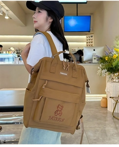 Detail of khaki oxford backpack showing embroidered bear pattern and side pockets
