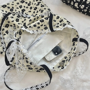 Detail of floral canvas tote bag featuring lace trim, magnetic closure and inner zip pocket