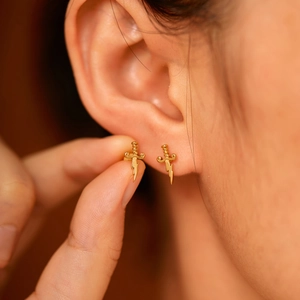 Macro shot of gold lightning dagger earrings worn by a model with a sharp elegant look