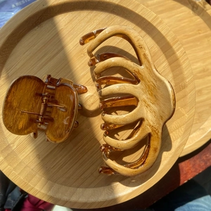 Detailed macro view of two amber tortoiseshell hair claws on a circular wooden tray