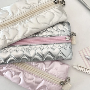 Detailed view of quilted heart pattern pencil cases in pearl white, silver, and pink