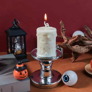 Close-up of Halloween ghost face pillar candle with flame on silver metallic holder