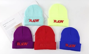 Detailed close-up of knit beanies in five vibrant colors featuring RAW embroidery detail