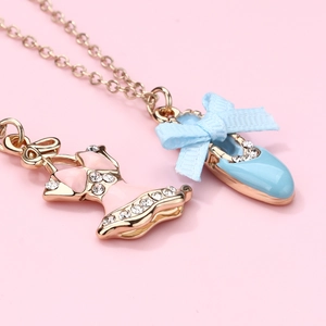 Dettaglio collana dorata con ciondoli a tutù e scarpetta blu con strass e fiocco