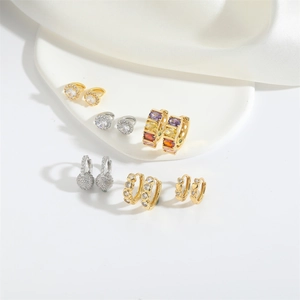 Chic gold and silver earrings with colorful zircons on white silk background
