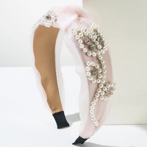 Pink mesh headband featuring pearl and rhinestone floral patterns on a white pedestal