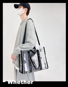 Detailed side view of clear PVC tote bag with black handles and spacious interior