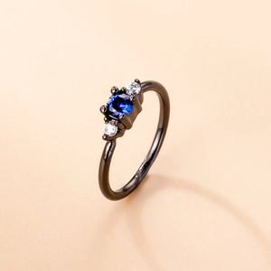 Black nose ring with blue center zircon and white side stones on a beige background