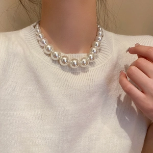 Close-up of large round gradient pearl necklace on model with elegant glossy finish