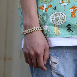Close-up of men's wrist wearing a chunky golden Cuban link bracelet with clear diamonds