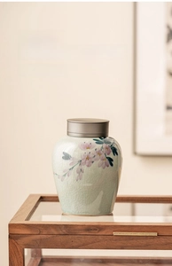 Close-up of ceramic tea jar with pale celadon crackle glaze and hand-painted floral pattern