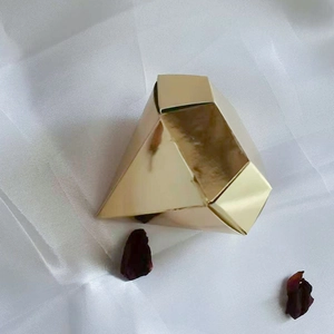 Elegant diamond-shaped golden candy gift box for weddings on a white silk background