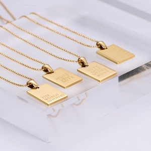 Detail view of gold rectangular charm necklaces with inspirational LOVE engravings