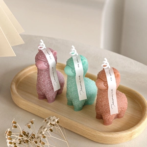 Detailed texture of alpaca scented candles in pink, mint green and orange colors
