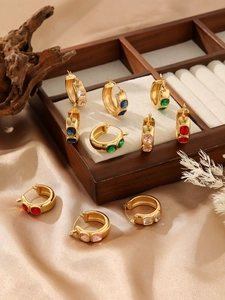 Detailed view of 18k gold hoop earrings with multi-colored cubic zirconia on silk fabric