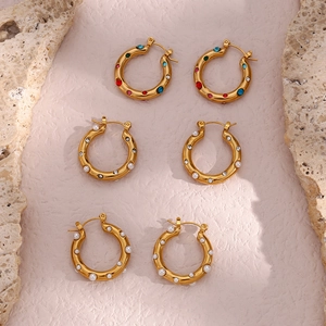 Detailed shot of gold earrings featuring colorful gemstones and pearl inlay designs