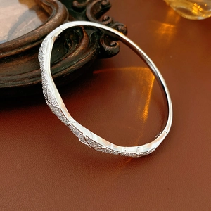 Macro detail of silver plated bangle featuring micro-pave cubic zirconia and hinged clasp