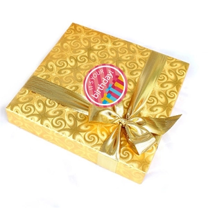 Macro detail of a gold gift box with texture, satin ribbon, and a birthday sticker