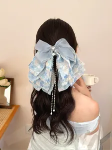 Détail d'une pince à cheveux à nœud fleuri bleu avec de longs glands de perles