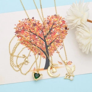 Detail of gold layered necklace set with heart gem, Mama moon and bird charms