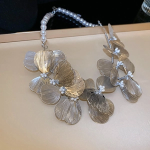 Macro shot of layered champagne gold metal flower petals and white pearls on necklace