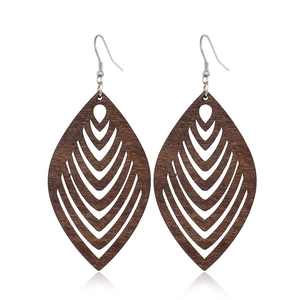 Macro detail of dark brown leaf-shaped wooden earrings with hollow texture and metal hooks