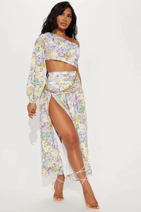 Detailed texture of floral one-shoulder long sleeve top and high-slit skirt with gold chain