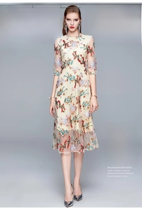 Close-up of elegant beige mesh dress featuring intricate colorful floral embroidery details