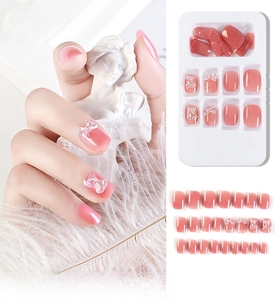 Detail of short square press-on nails in sheer pink with 3D bow and bear charms