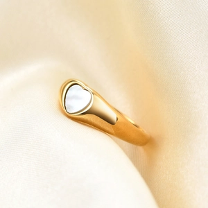 Macro view of 18K gold stainless steel ring with white shell heart inlay on silk