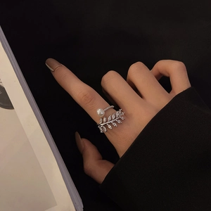 Silver leaf zircon ring with pearl accent on model finger against black background