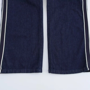 Dettaglio ravvicinato di pantaloni di jeans blu scuro con strisce laterali bianche e cuciture
