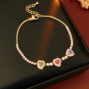 Detail of 18k gold plated tennis bracelet with green red and purple heart crystals