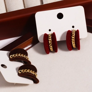 Detailed close-up of heart-shaped velvet earrings in wine red and dark brown with gold chains