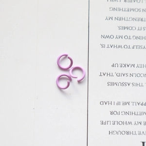 Detailed view of three pink metal jump rings on a white surface for DIY jewelry making