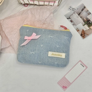 Detail of light blue denim coin purse featuring embroidery, pink bow and zip closure