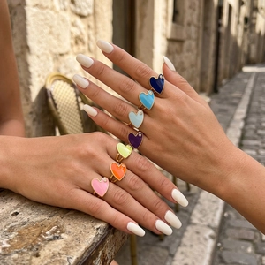 Detailed view of colorful enamel heart rings with tiny rhinestones on gold band