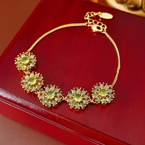 Macro shot of gold plated floral bracelet with green zircon petals on a dark wood surface