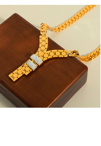 Close-up of a 18k gold-plated Y-shaped pendant necklace with cubic zirconia on a wooden box