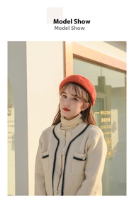 Detailed view of women's red wool beret styled with elegant cream knit cardigan