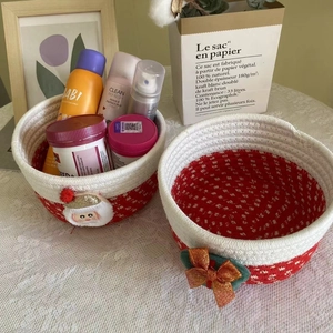 Handwoven cotton rope Christmas baskets with Santa Claus and red bow on lace tablecloth
