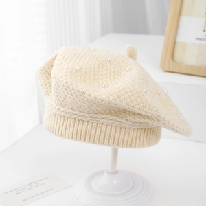 Close-up of cream knit beret with pearl embellishments and ribbed edge detail