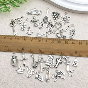 Macro shot of assorted antique silver alloy charms with ruler for size scale reference