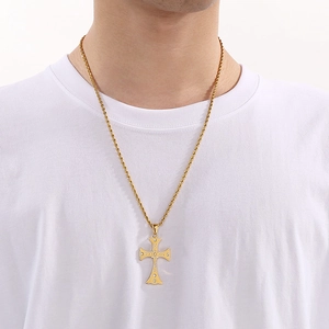 Detail of a gold rope chain with a diamond-encrusted cross pendant on a white shirt