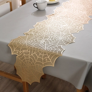 Close-up of golden spiderweb table runner with hollow mesh lace on dining table